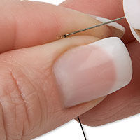 Fingers holding thread and a needle